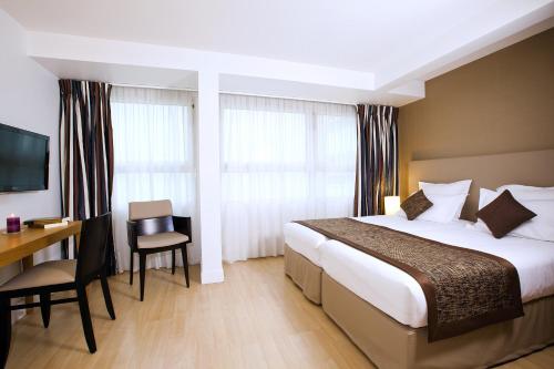 a hotel room with a bed and a desk and a television at Residhome Paris Opéra in Paris