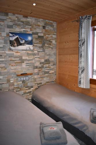 two beds in a room with a stone wall at Chalet le Petit Ramoneur in Châtel