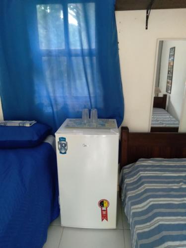 a small refrigerator in a room with a bed at SUITES E CHALES PRIVADOS Rock's&Rose's home in Camburi