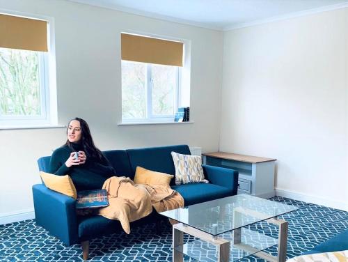 a woman sitting on a blue couch in a living room at Buttermere Court Hotel in Buttermere