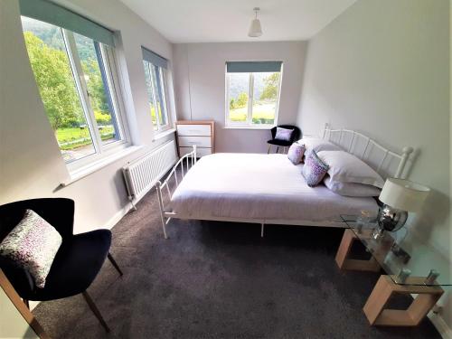 a bedroom with a bed and a table and two windows at Buttermere Court Hotel in Buttermere