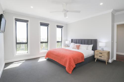 a bedroom with a bed with an orange blanket and windows at Indulge Luxury Homes - Dockside Marina in Mildura