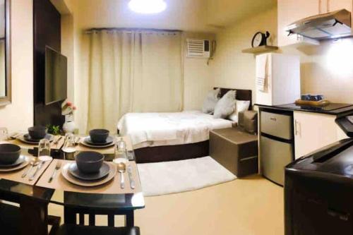 Habitación pequeña con cama y mesa con platos. en Zen Living Condo at Avida Atria Tower 2, en Iloilo City