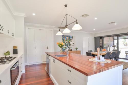 a kitchen with white cabinets and a wooden counter top at Indulge Luxury Homes - Dockside Marina in Mildura