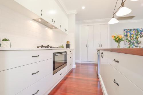 a kitchen with white cabinets and a wooden floor at Indulge Luxury Homes - Dockside Marina in Mildura