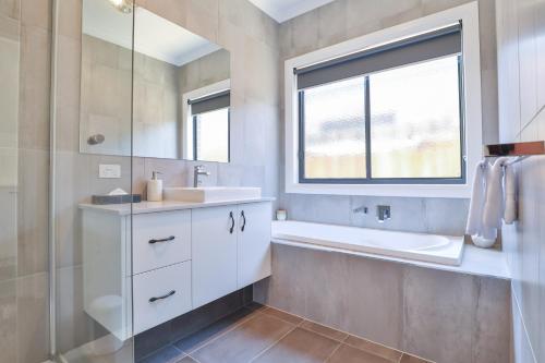 a bathroom with a sink and a tub and a window at Indulge Luxury Homes - Dockside Marina in Mildura