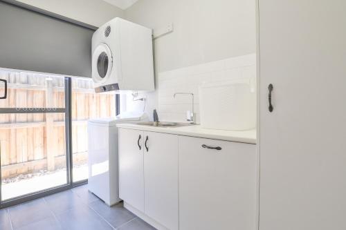 a white kitchen with a sink and a window at Indulge Luxury Homes - Dockside Marina in Mildura