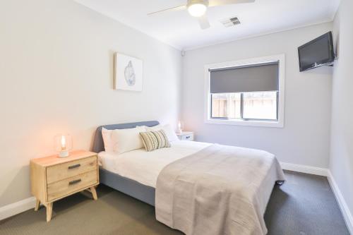 a bedroom with a bed with a night stand and a window at Indulge Luxury Homes - Dockside Marina in Mildura