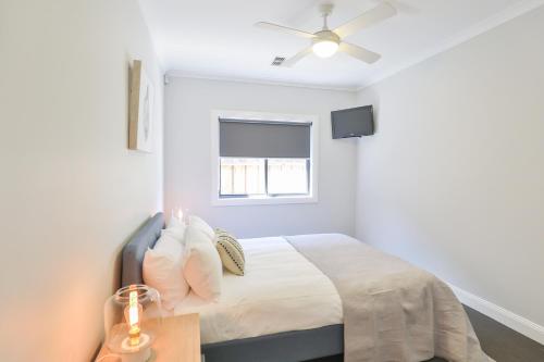 a white bedroom with a bed and a window at Indulge Luxury Homes - Dockside Marina in Mildura