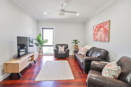 a living room with a leather couch and a tv at Indulge Luxury Homes - Dockside Marina in Mildura