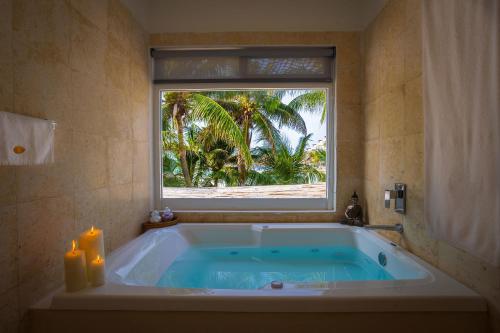 a bathroom with a tub with a window and two candles at Lotus Beach Hotel - Adults Only in Isla Mujeres