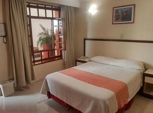 a hotel room with a bed and a window at Hotel Santa Rosa in Oaxaca City