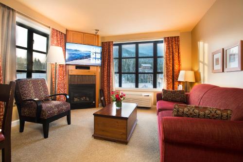 a living room with a red couch and a fireplace at Sundial Hotel in Whistler