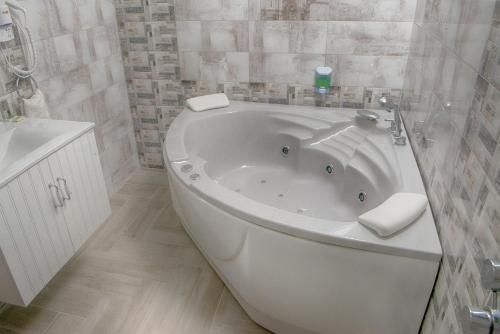 uma banheira branca numa casa de banho com azulejos em Sweet Life Family Hotel em Tsigov Chark