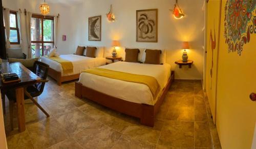 a bedroom with two beds and a living room at Casa Hridaya Hotel Boutique in Holbox Island