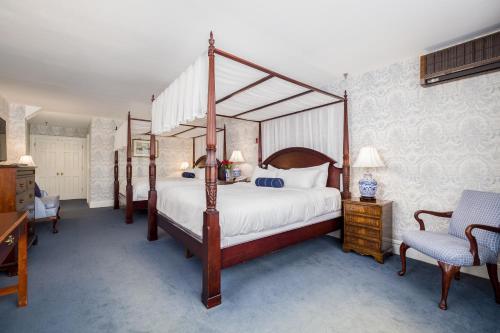 a bedroom with a four poster bed and a chair at Simsbury 1820 House in Simsbury