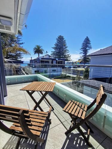 two wooden chairs and a table on a balcony at The Anchorage Apartments in Mount Maunganui
