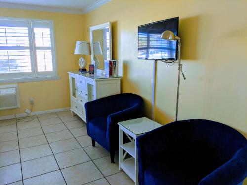 a living room with a blue chair and a tv at Coral Sands Inn in Ormond Beach