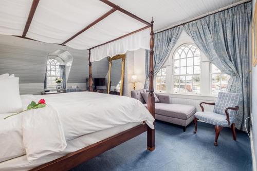 Simsbury 1820 House في Simsbury: غرفة نوم بها سرير مظلة وكرسي ونافذة