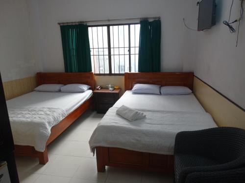 two beds in a room with green curtains at Thuong Hai Hotel in Ho Chi Minh City