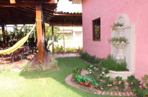 a pink house with a hammock in the yard at Casa de Quincha in Las Tablas