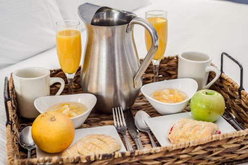 a tray with a basket of breakfast foods and orange juice at Simsbury 1820 House in Simsbury