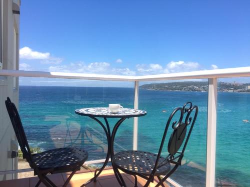 a table and chairs on a balcony with the ocean at Manly Waterfront Beach Stay in Queenscliff