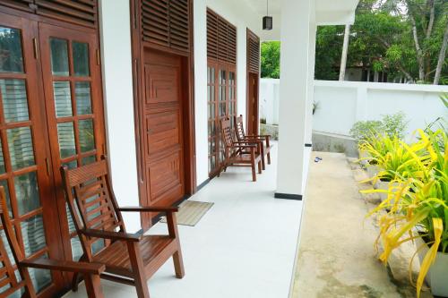 a row of wooden chairs sitting on a porch at Verona D' Oro in Dickwella