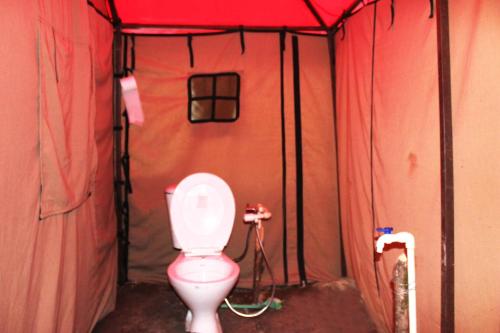 a bathroom with a toilet in a red tent at Chopta Mount Holiday Camp & Resort in Ukhimath