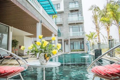 um vaso de flores amarelas sentado numa mesa ao lado de um edifício em Ninh Bình Premier hotel em Ninh Binh