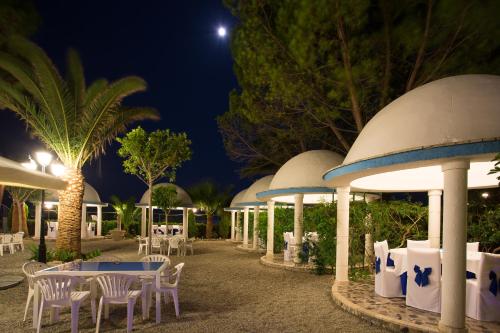 un grupo de mesas y sillas por la noche en Residence Regina, en Marina di Gioiosa Ionica