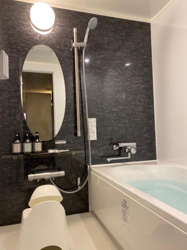 ein Badezimmer mit einer Badewanne, einem WC und einem Spiegel in der Unterkunft ホテル シンドバッド滝沢店 Adult Only in Barajima