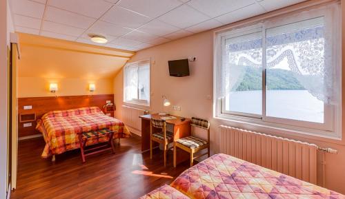 ein Hotelzimmer mit 2 Betten und einem Fenster in der Unterkunft Logis Hôtel Belle Vue in Les Ancizes-Comps