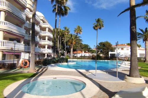 a swimming pool in front of a building with palm trees at Casablanca - Playa Romana in Alcossebre