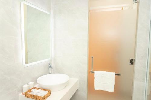 a white bathroom with a sink and a mirror at La Casa Tuy Hòa in Tuy Hoa