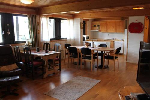 a dining room with tables and chairs and a kitchen at Bergfosshytta 1 sør in Ron