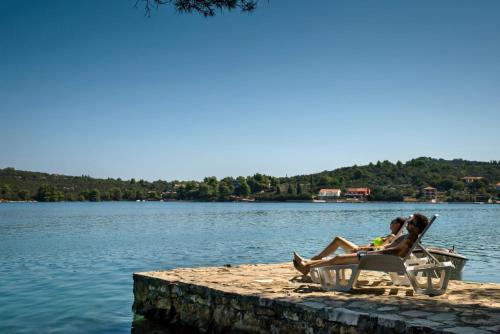 two people sitting in a chair on a dock near the water at Feel Dugi Otok - Apartment Sofia in Luka