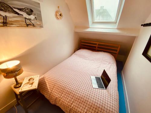 um pequeno quarto com uma cama com um computador portátil em La Cabourgeaise em Cabourg