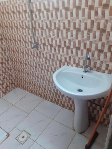 ein weißes Waschbecken im Bad mit einer gefliesten Wand in der Unterkunft Alkithri Apartments for Singls in Muhayil