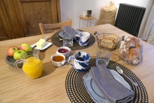 une table avec un petit-déjeuner composé de pain et de jus d'orange dans l'établissement Les Tilleuls, à Saint-Jean-dÊ¼Avelanne