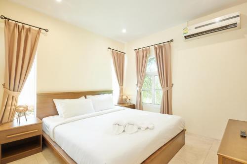 a bedroom with a large white bed with two rings on it at Talay Hotel and Villa Cha-am in Cha Am