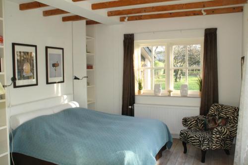 a bedroom with a bed and a chair and a window at B&B De Sprokkeltuin in Beuningen
