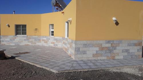 a yellow building with a brick patio at Finca Los Rosales in La Lajita