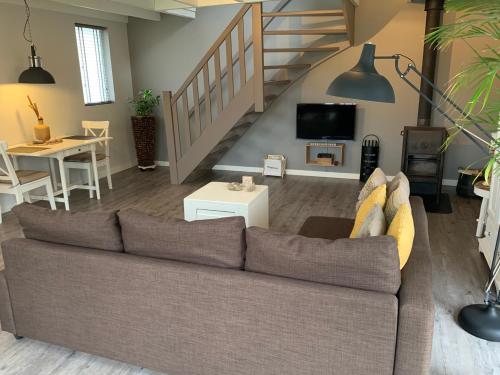 a living room with a couch and a staircase at Heitse B&B en vakantiewoning in Heythuysen