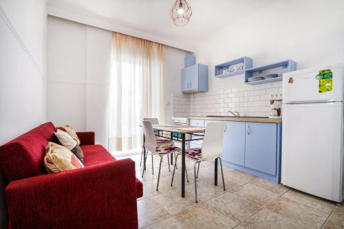 a kitchen with a red couch and a table with chairs at Dimitra Beach Apartments - Nea Karvali Kavala in Néa Karváli