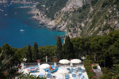 a pool with chairs and umbrellas next to the water at Hotel Villa Brunella in Capri