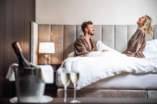 a man and a woman sitting in bed at Prunner Luxury Suites - Adults Only in Schenna