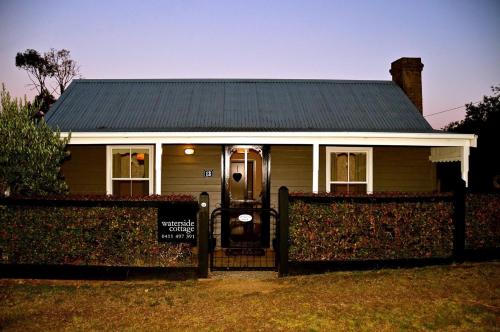 a house with a gate in front of it at Waterside Cottage in Daylesford