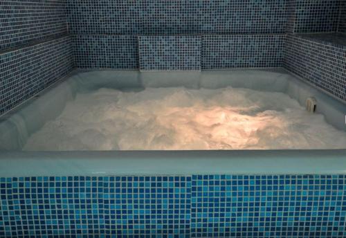 a hot tub filled with snow in a tiled room at Zan Hotel in Voineasa