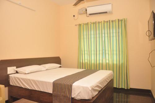a bedroom with a bed and a green curtain at Hotel Aishwariyam in Tirukkadaiyūr